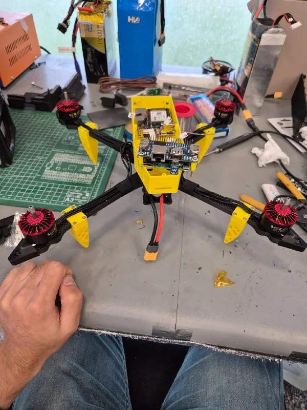 A yellow-framed drone with motors and electronics fitted on a workshop bench